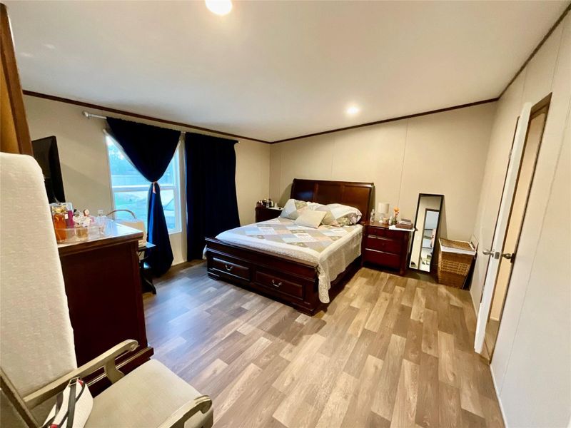 Bedroom 4. Máster  featuring wood-finish flooring, light-toned wall paneling, and a window with dark drapery