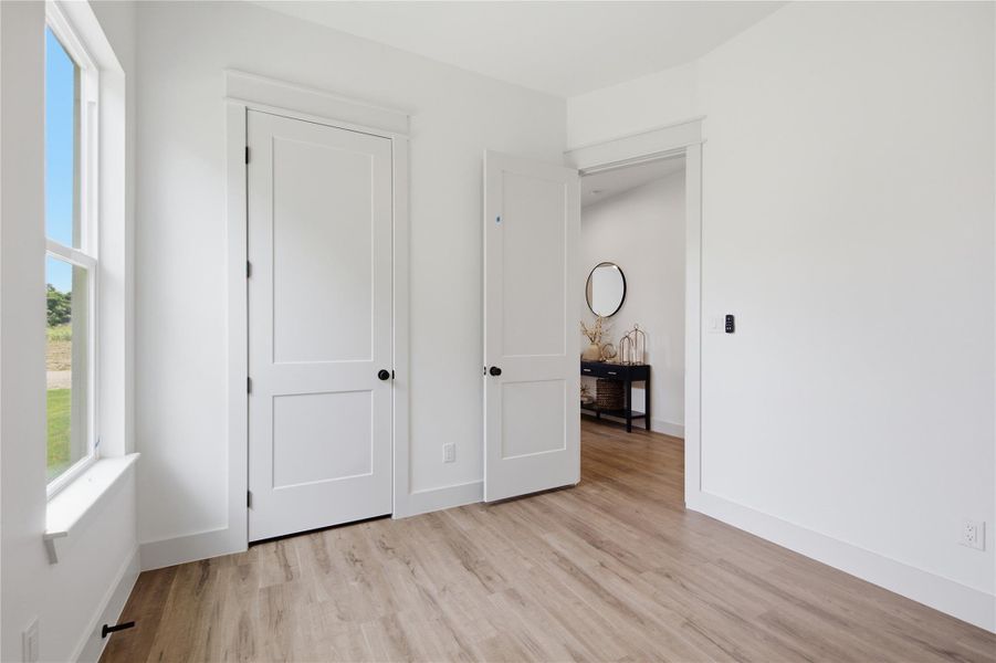 An airy bedroom with resilient wood flooring and clean, minimalist doors for a modern aesthetic. An airy bedroom with resilient wood flooring and clean, minimalist doors for a modern aesthetic.