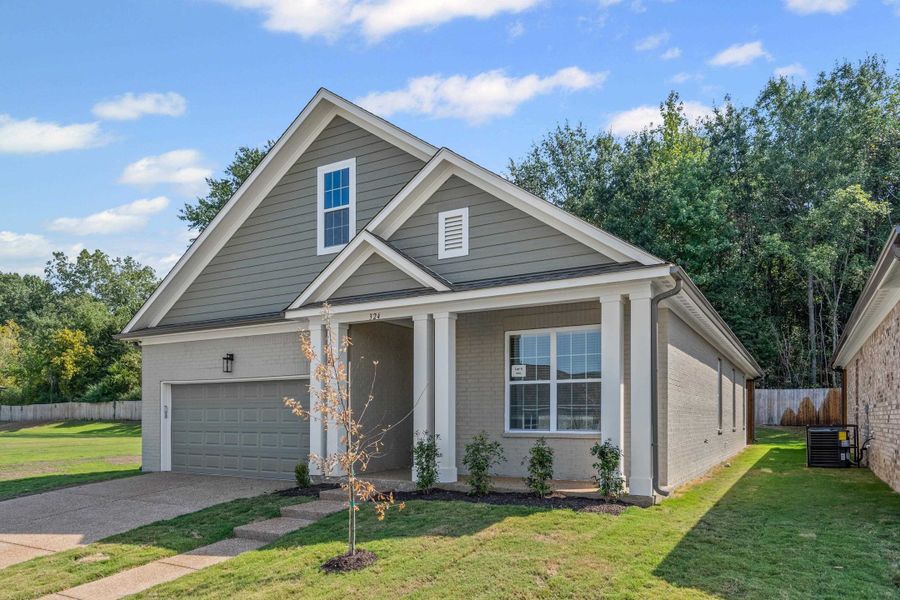 View of front facade with covered porch, brick siding, and driveway