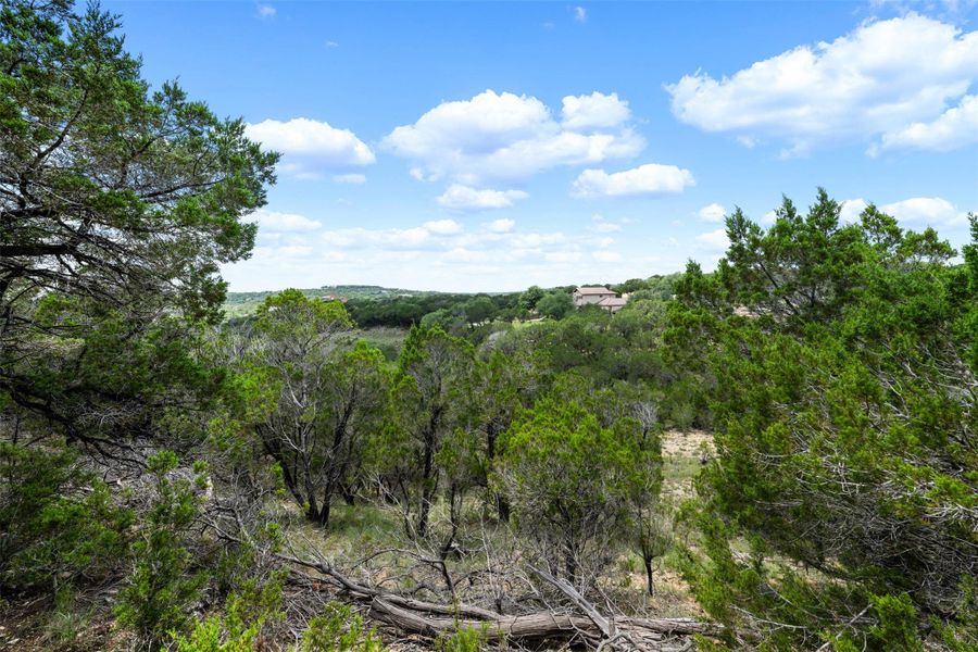A tranquil landscape offers distant views of residences nestled within a lush, verdant canopy. A tranquil landscape offers distant views of residences nestled within a lush, verdant canopy.