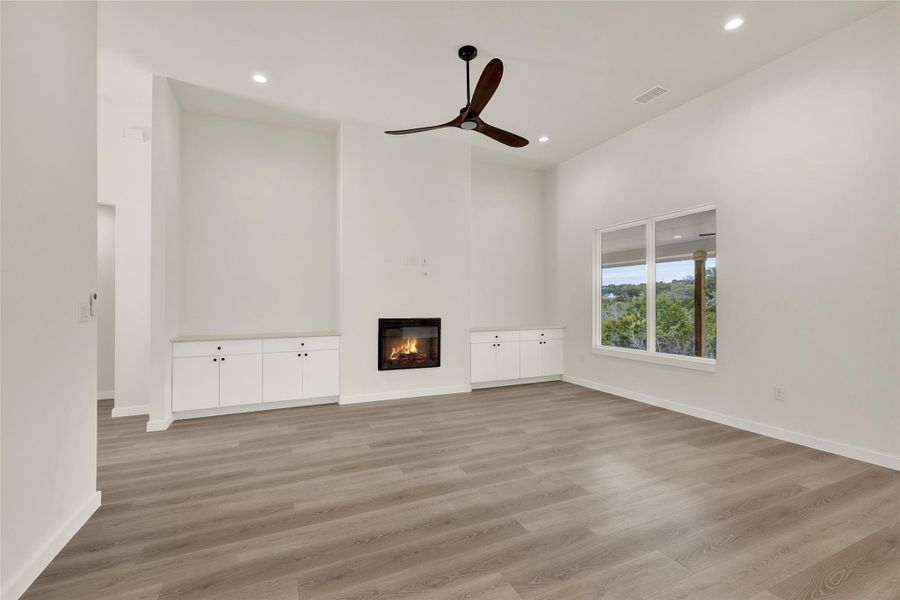 Unfurnished living room with a glass covered fireplace, ceiling fan, light wood-style flooring, and recessed lighting