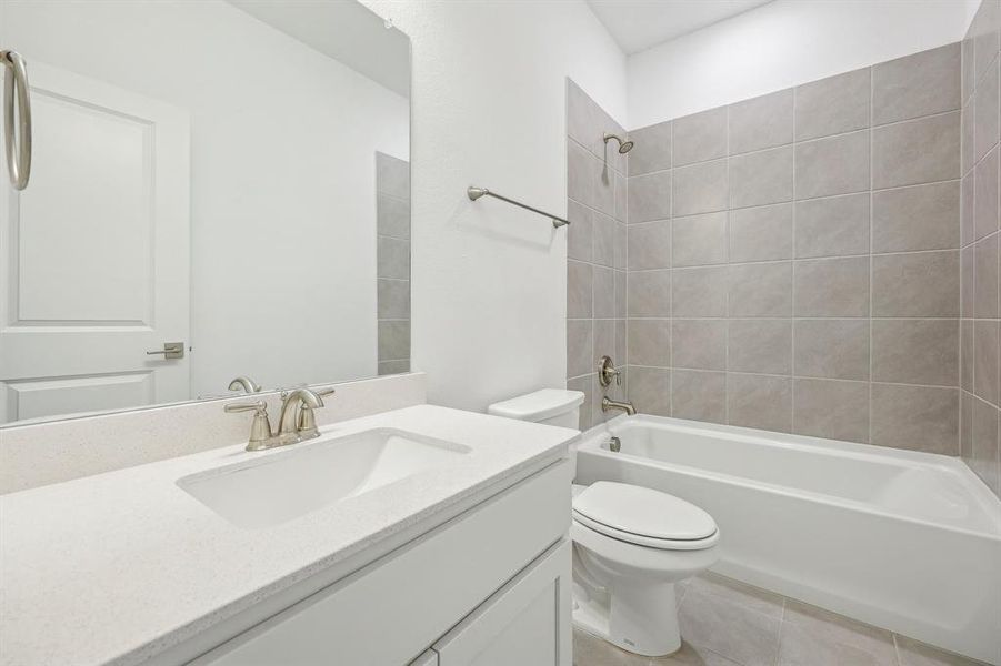 Full bathroom with tiled shower / bath combo, vanity, and toilet