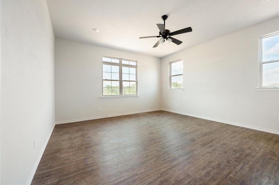 Empty room featuring dark wood-type flooring and ceiling fan