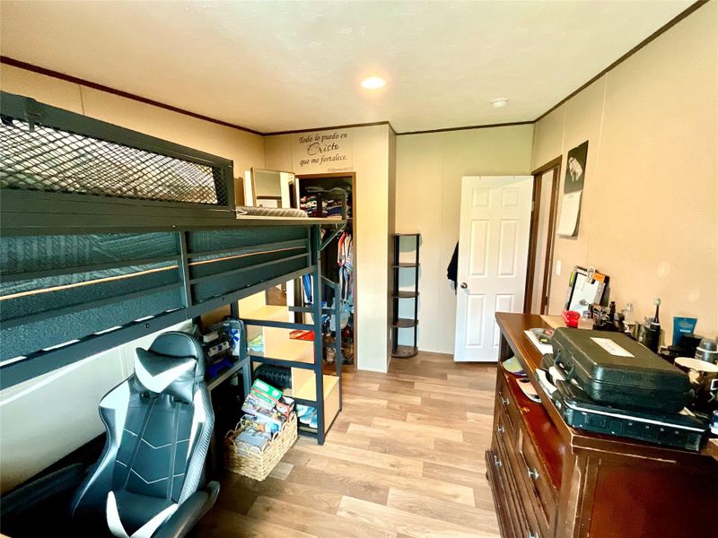 Room 1 featuring wood-finish flooring, recessed lighting, a white interior door, and a built-in closet with shelving