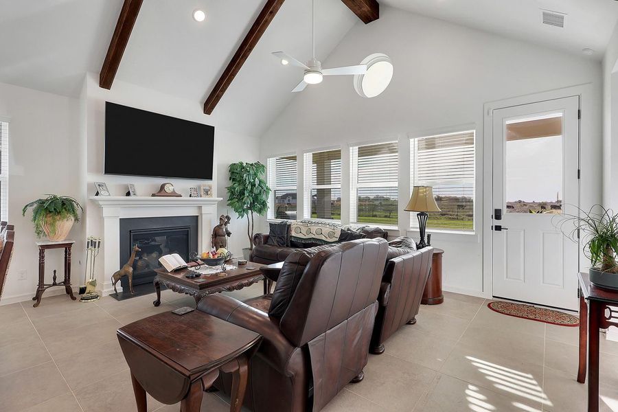 Living room features high ceilings with exposed wooden beams, a cozy fireplace, and large windows providing natural light and scenic views.