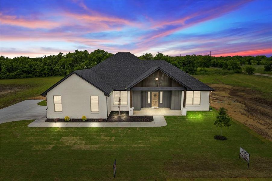 View of front of property with a lawn and roof with shingles