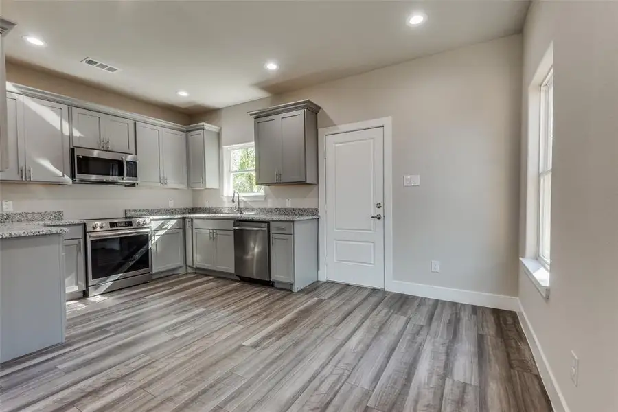 Kitchen featuring appliances with stainless steel finishes, light wood-style floors, gray cabinetry, and a sink