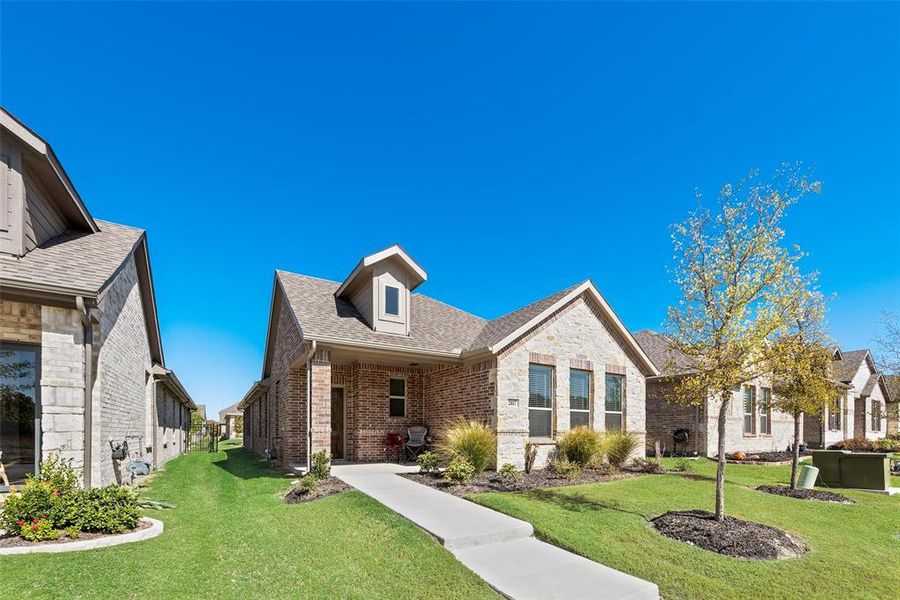 View of front of home featuring a front lawn, covered porch, brick siding, and roof with shingles View of front of home featuring a front lawn, covered porch, brick siding, and roof with shingles