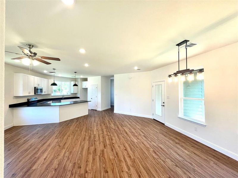 Kitchen with kitchen peninsula, pendant lighting, white cabinets, and hardwood / wood-style flooring