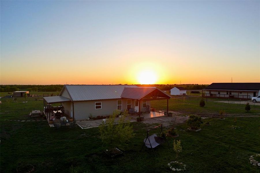 Back of house at dusk with a yard, a patio area, and metal roof