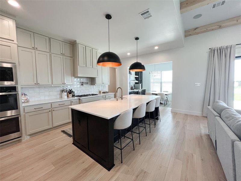 Kitchen featuring open floor plan, backsplash, recessed lighting, pendant lighting, and dark cabinets
