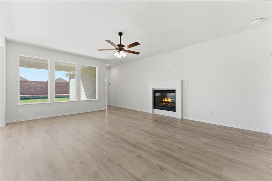 Unfurnished living room featuring a glass covered fireplace, light wood-style flooring, and a ceiling fan