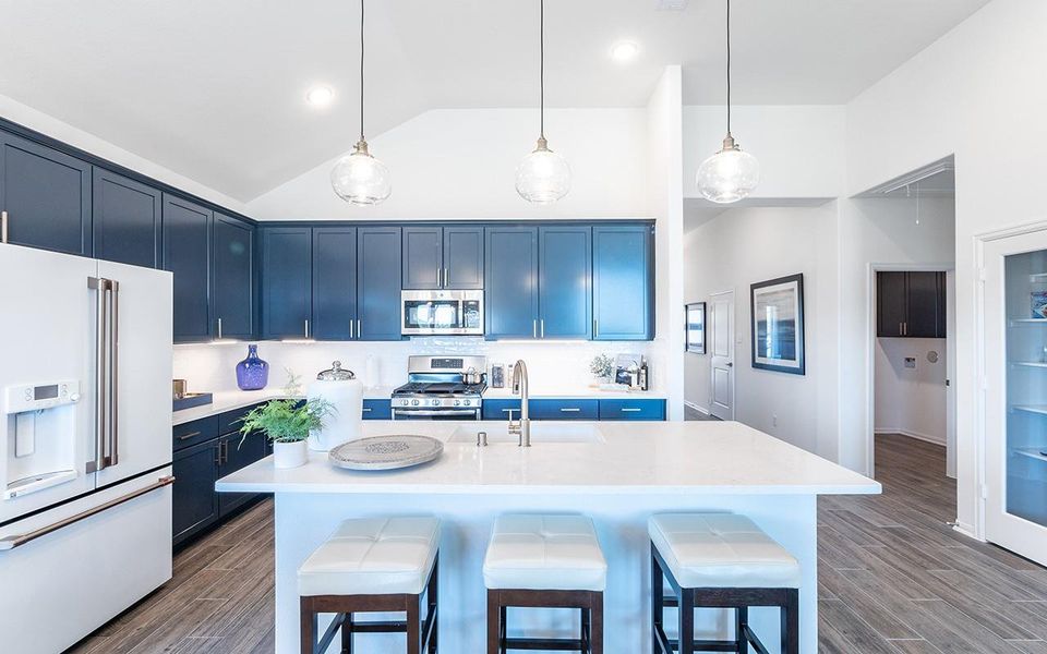 Kitchen featuring appliances with stainless steel finishes, blue cabinets, a sink, light countertops, and high vaulted ceiling Kitchen featuring appliances with stainless steel finishes, blue cabinets, a sink, light countertops, and high vaulted ceiling