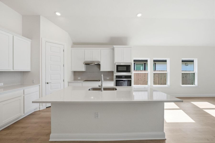 Kitchen with white cabinetry, tasteful backsplash, light wood-style flooring, light stone countertops, and recessed lighting Kitchen with white cabinetry, tasteful backsplash, light wood-style flooring, light stone countertops, and recessed lighting