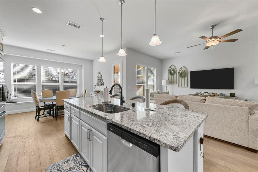 Kitchen featuring pendant lighting, white cabinets, sink, a kitchen island with sink, and stainless steel dishwasher