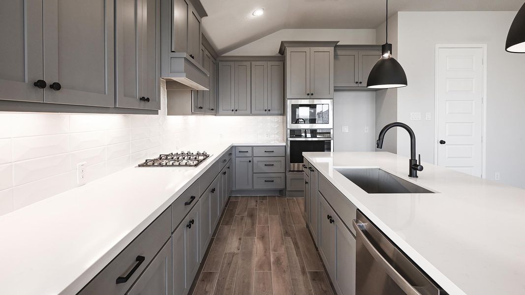 Kitchen with dark wood-type flooring, a sink, gray cabinets, and stainless steel appliances Kitchen with dark wood-type flooring, a sink, gray cabinets, and stainless steel appliances