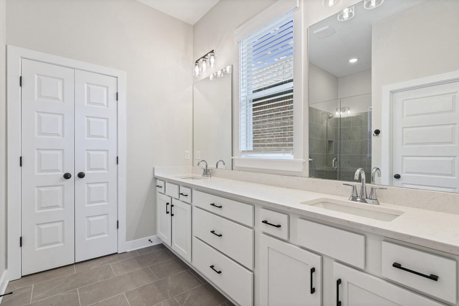 Bathroom featuring a double vanity with white cabinetry, light-colored countertops, and chrome fixtures Bathroom featuring a double vanity with white cabinetry, light-colored countertops, and chrome fixtures
