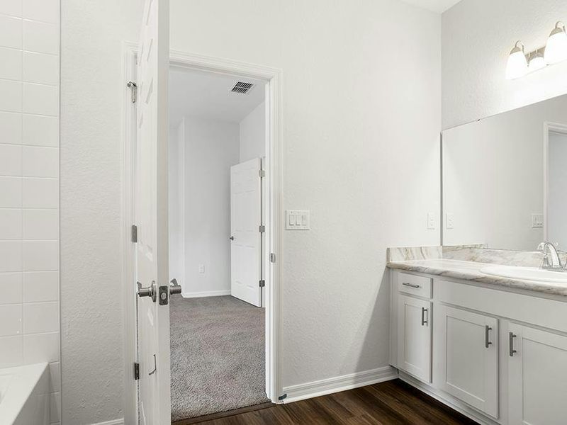 Bedroom 2 includes an en-suite bath with a tub/shower combo, a private toilet, and a linen closet - Everly by Highland Homes