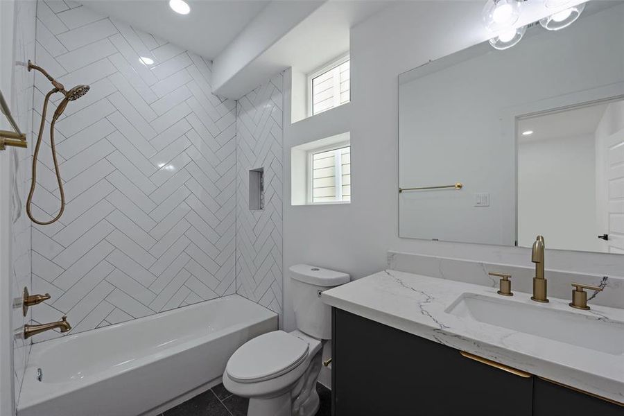 The second of three full baths features tub-to-ceiling tiles, a tub and shower combo, and a nice-sized vanity.