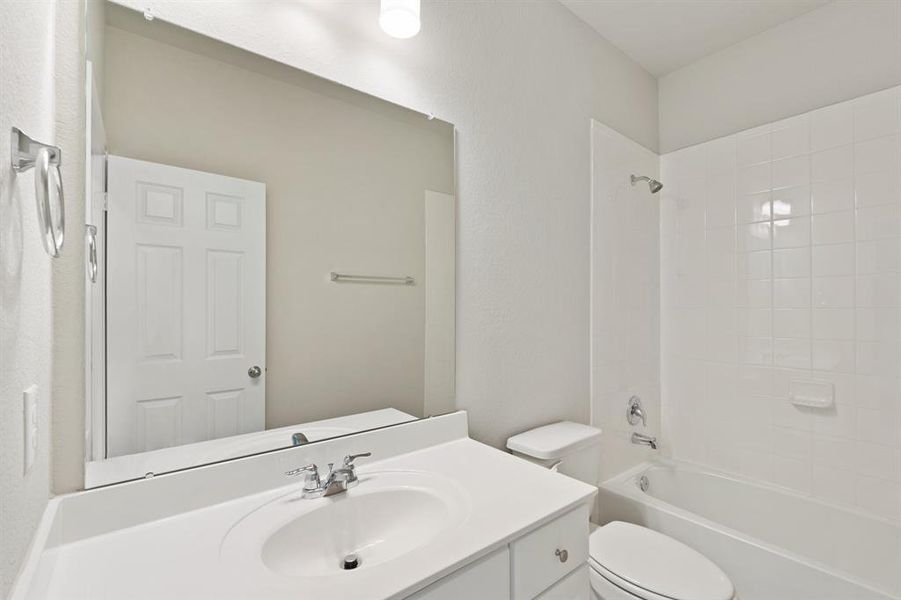 The secondary bath features tile flooring, white cabinetry and light countertops and a shower/tub combo. Perfect for accommodating any visiting family and friends.