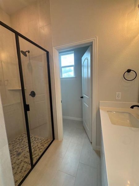 Walk-in shower with a frameless glass enclosure and mosaic tile flooring