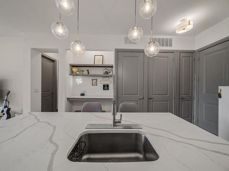 Kitchen featuring light stone counters, hanging light fixtures, and open shelves Kitchen featuring light stone counters, hanging light fixtures, and open shelves