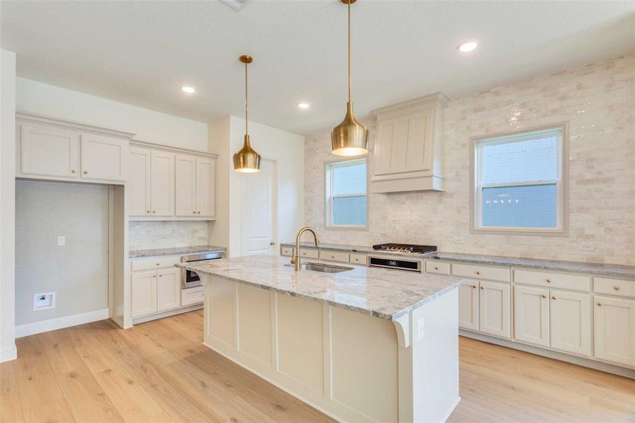 Kitchen with decorative light fixtures, a healthy amount of sunlight, light hardwood / wood-style floors, and sink