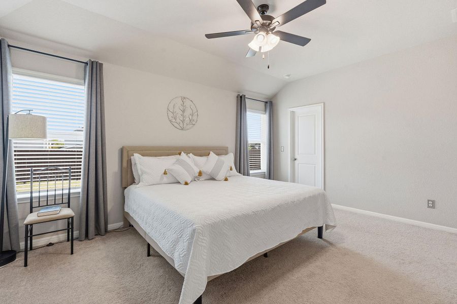 Bedroom featuring light colored carpet, vaulted ceiling, and a ceiling fan Bedroom featuring light colored carpet, vaulted ceiling, and a ceiling fan