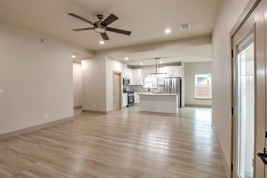Unfurnished living room featuring light wood-type flooring, ceiling fan, and recessed lighting