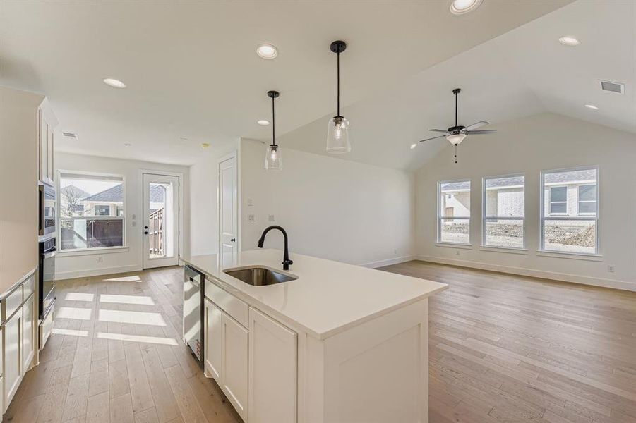 Kitchen featuring white cabinets, open floor plan, healthy amount of natural light, light wood-type flooring, and lofted ceiling Kitchen featuring white cabinets, open floor plan, healthy amount of natural light, light wood-type flooring, and lofted ceiling