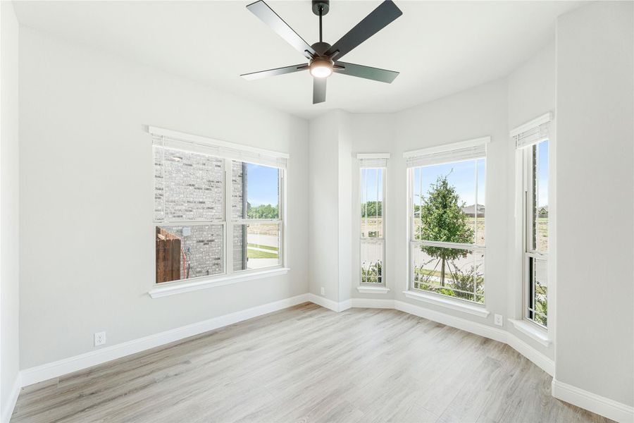 Empty room with light wood floors, ceiling fan, and large windows with outdoor views