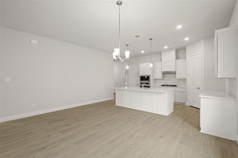 Kitchen featuring stainless steel appliances, recessed lighting, decorative backsplash, light wood finished floors, and light countertops