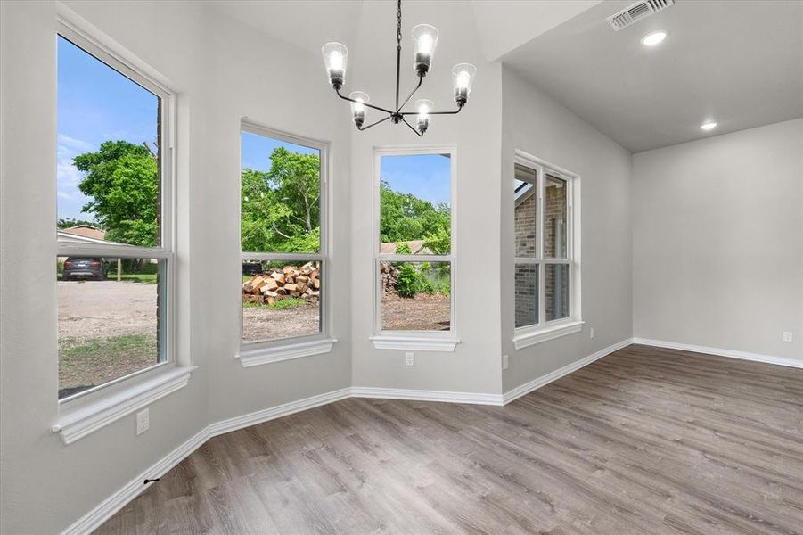 Dining area featuring wood-finish flooring, vaulted ceilings, and a contemporary chandelier