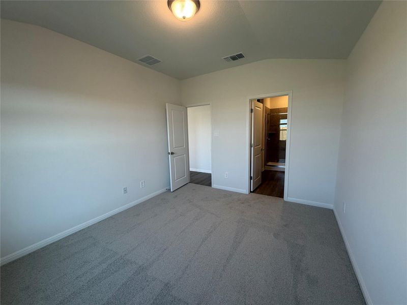 Unfurnished bedroom with lofted ceiling, carpet, and connected bathroom