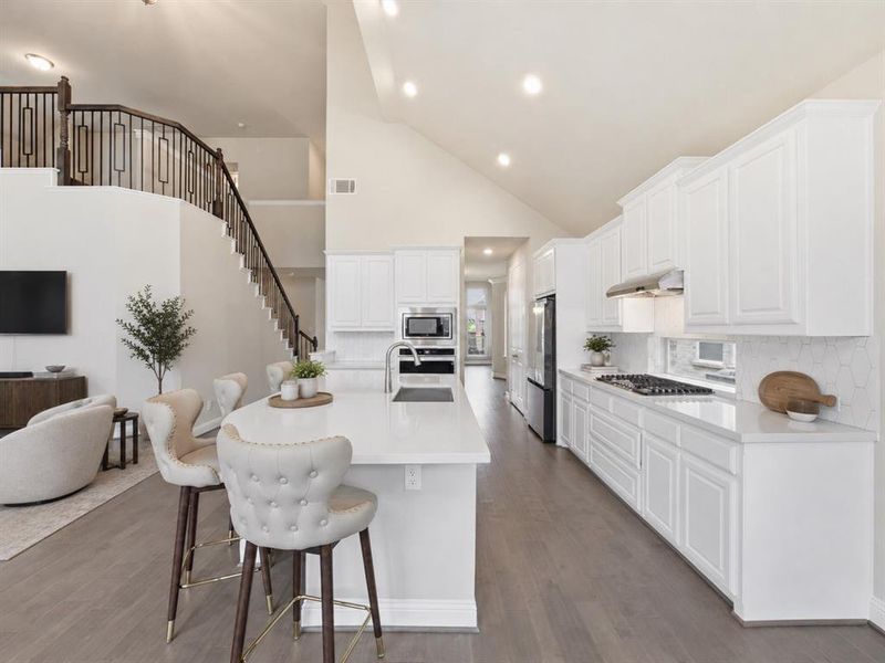 Contemporary kitchen featuring white cabinetry, light-tone countertops, stainless steel appliances, and a hexagonal tile backsplash