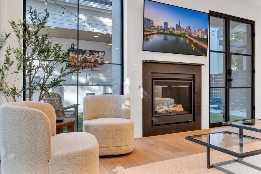 Living area featuring wood finished floors and a glass covered fireplace Living area featuring wood finished floors and a glass covered fireplace