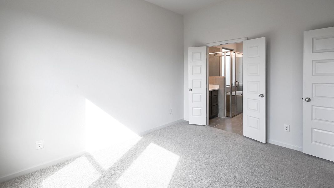 Unfurnished bedroom with light colored carpet and connected bathroom