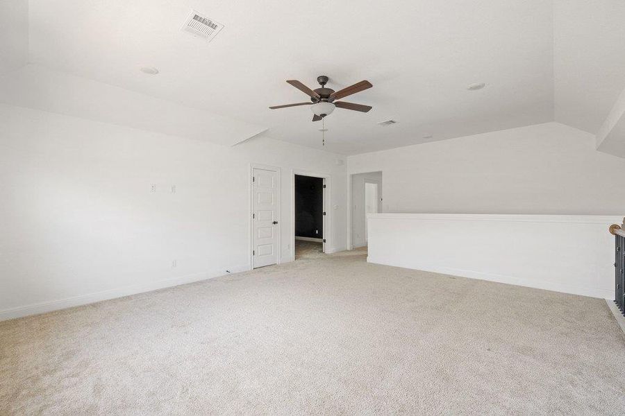 Spare room with light carpet, a ceiling fan, and lofted ceiling Spare room with light carpet, a ceiling fan, and lofted ceiling