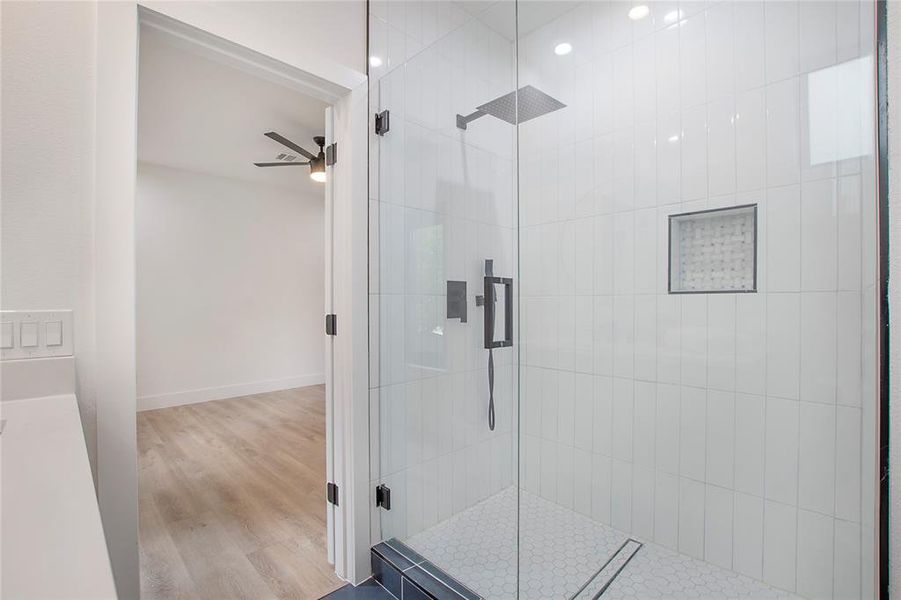 Bathroom featuring ceiling fan, hardwood / wood-style flooring, and a shower with door