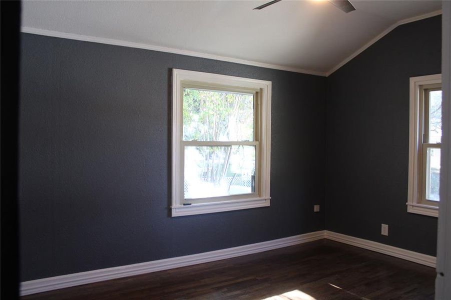 Spare room with dark wood-type flooring, vaulted ceiling, crown molding, and a ceiling fan Spare room with dark wood-type flooring, vaulted ceiling, crown molding, and a ceiling fan