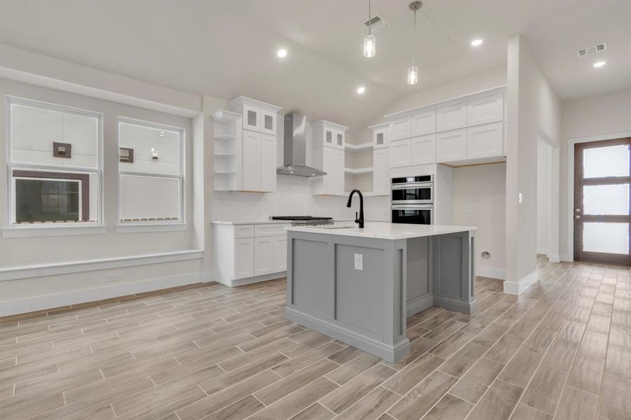 Culinary dreams come alive in this kitchen, featuring white cabinetry and an island with a breakfast bar.