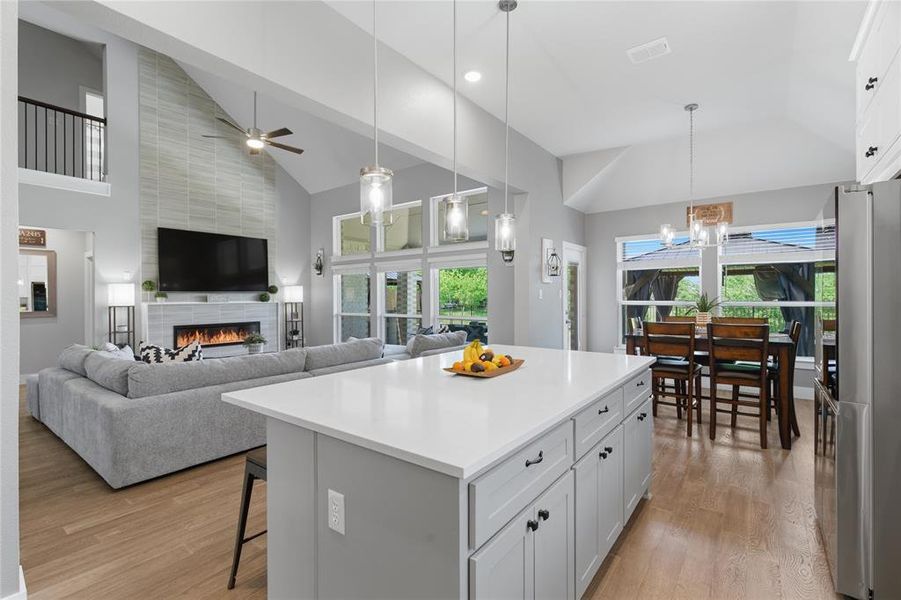 Vaulted ceilings highlight this open-concept living space, featuring wood-finish flooring throughout