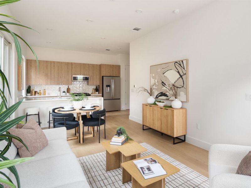 Open-concept living space featuring wood-finish flooring, a kitchen with flat-panel wood cabinetry, a tile backsplash, and stainless steel appliances