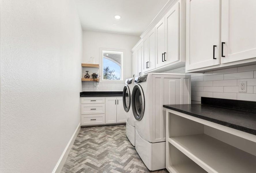 Laundry room with independent washer and dryer, brick flooring, and cabinet space