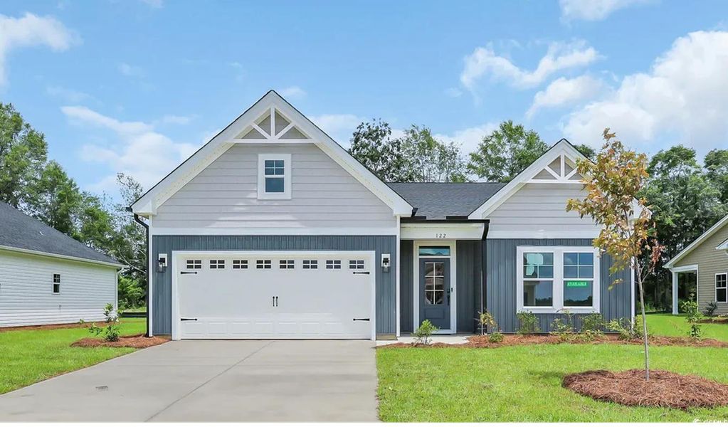 View of front facade featuring a front lawn, board and batten siding, and concrete driveway