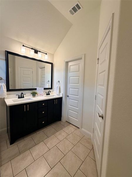 Bathroom featuring a dual vanity with a white countertop, two undermount sinks, and dark cabinetry Bathroom featuring a dual vanity with a white countertop, two undermount sinks, and dark cabinetry