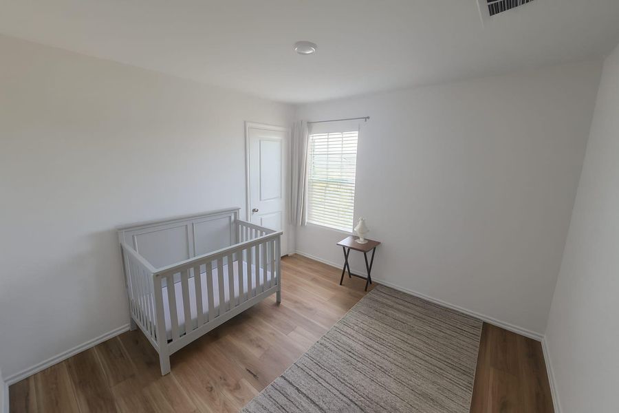 Bedroom featuring light wood-style floors and a crib Bedroom featuring light wood-style floors and a crib