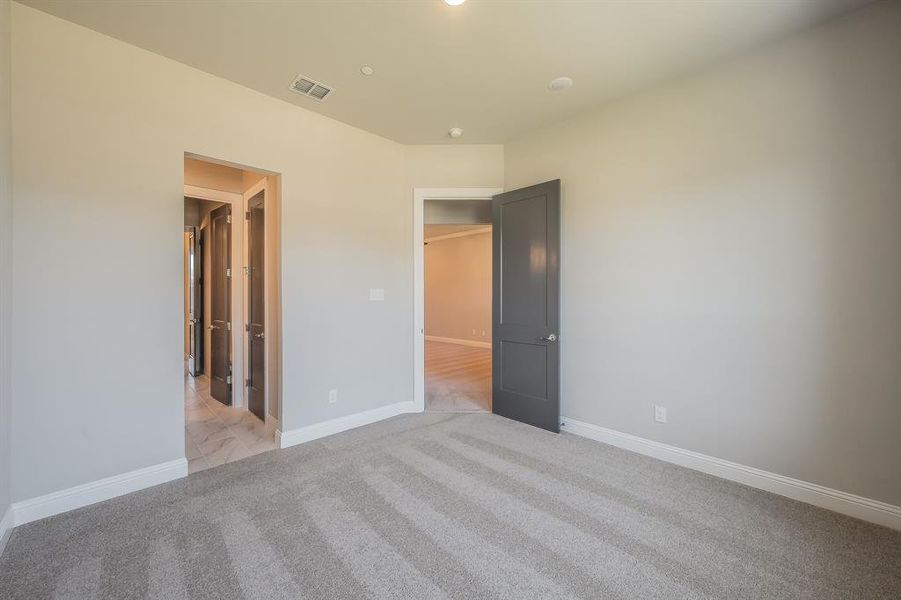 Carpeted room featuring light gray walls, white baseboards, a dark gray interior door, and a recessed ceiling light