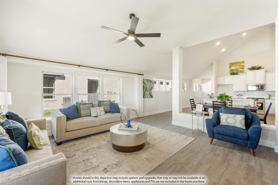 Open living room with hardwood floors, ceiling fan, and view into kitchen and dining area