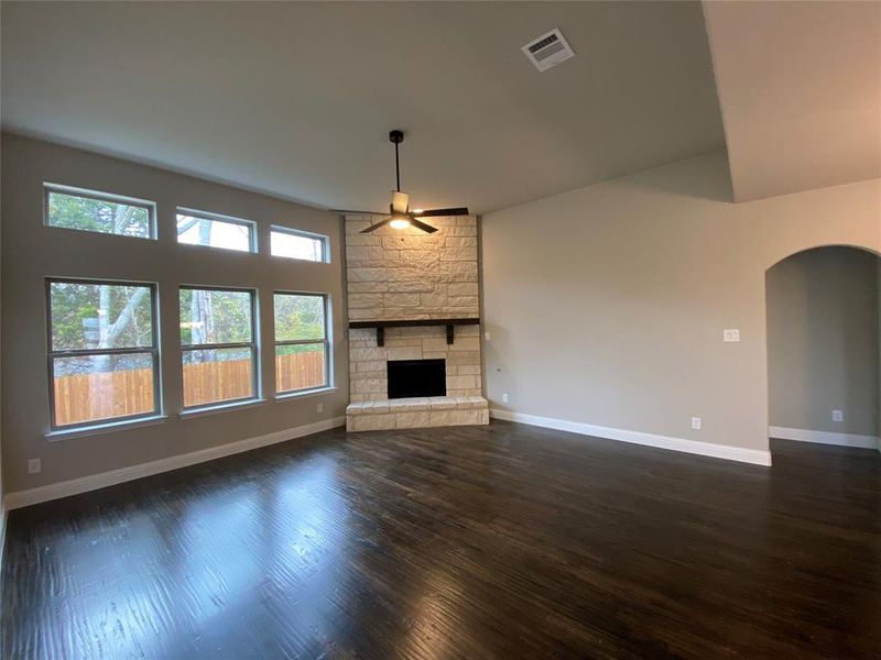 Family room offers a wall of windows, Ebony hardwoods, stone gas fireplace, and ceiling fan Family room offers a wall of windows, Ebony hardwoods, stone gas fireplace, and ceiling fan